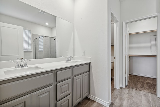 full bath featuring wood finish floors, a sink, a spacious closet, and a shower stall