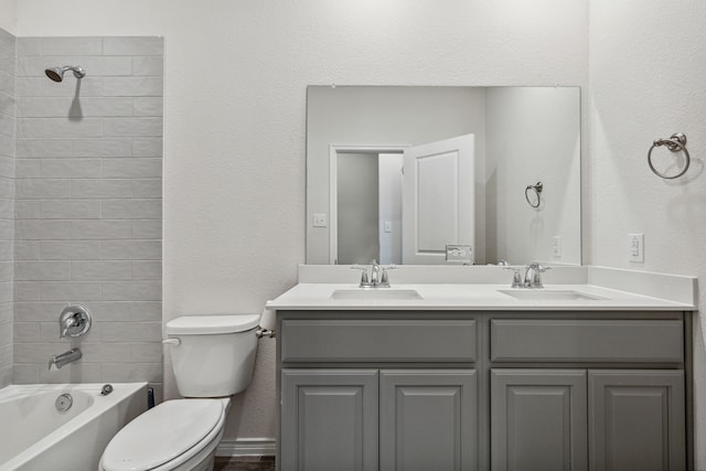 full bathroom with toilet, double vanity, a sink, and washtub / shower combination