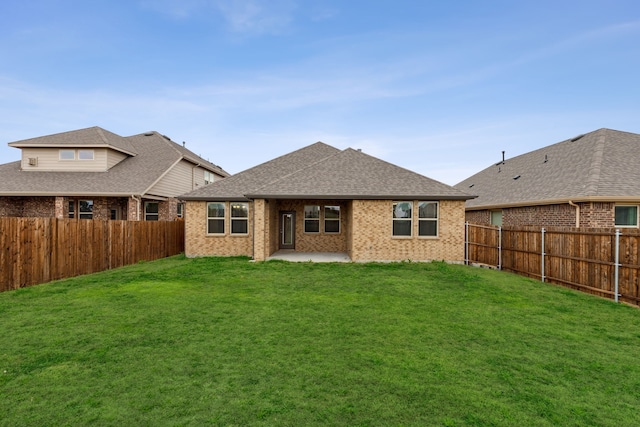 rear view of house featuring brick siding, a yard, a patio, a shingled roof, and a fenced backyard