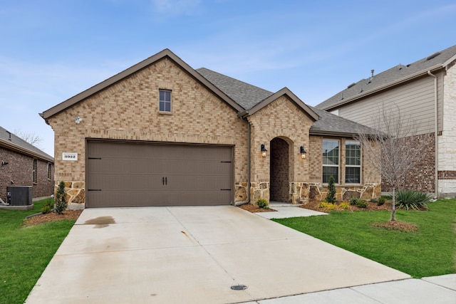 french country style house featuring a shingled roof, concrete driveway, a garage, cooling unit, and a front lawn