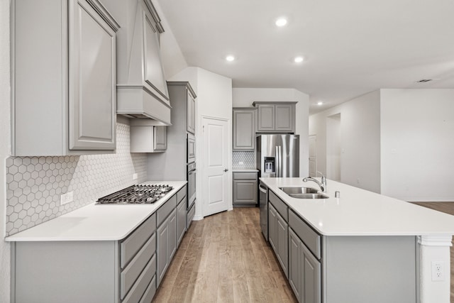 kitchen with stainless steel appliances, light countertops, a sink, and gray cabinetry