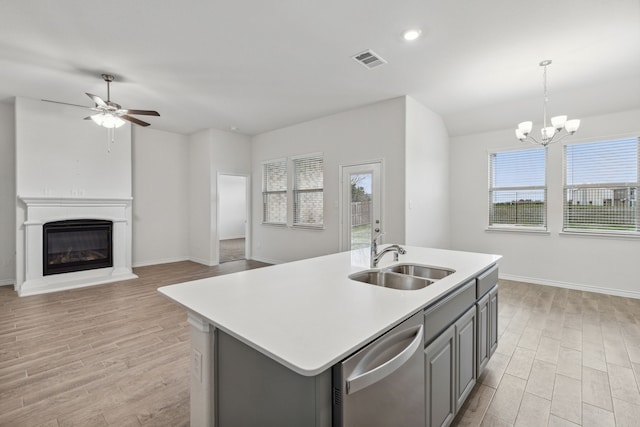 kitchen featuring light countertops, hanging light fixtures, open floor plan, a kitchen island with sink, and dishwasher