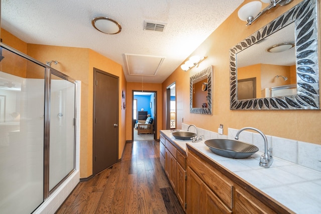 ensuite bathroom with wood finished floors, a sink, visible vents, and a shower stall