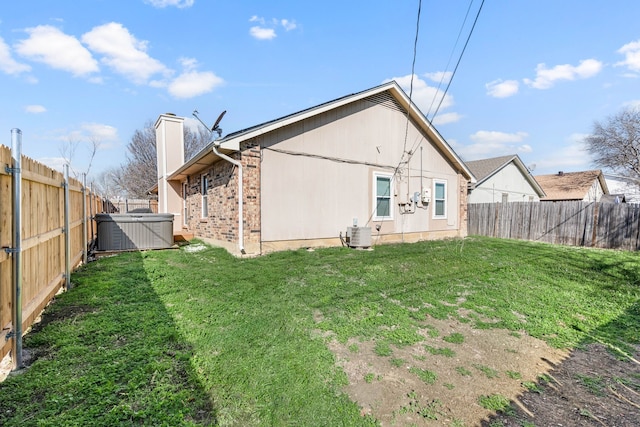 back of house with a fenced backyard, central air condition unit, a chimney, and a hot tub