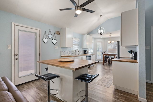 kitchen featuring a sink, butcher block countertops, a breakfast bar, white cabinetry, and dark wood-style flooring