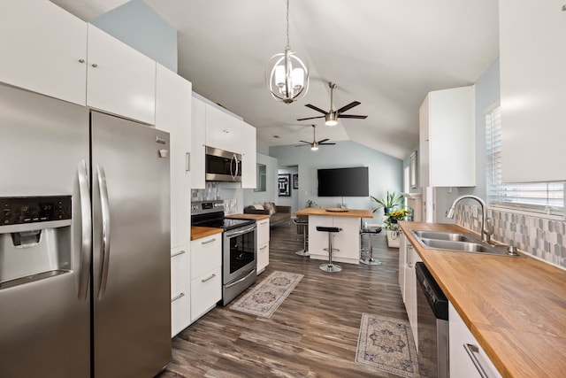 kitchen with a sink, butcher block counters, appliances with stainless steel finishes, white cabinets, and dark wood-style flooring