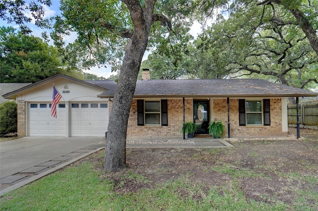 ranch-style home with a garage, a chimney, concrete driveway, and brick siding