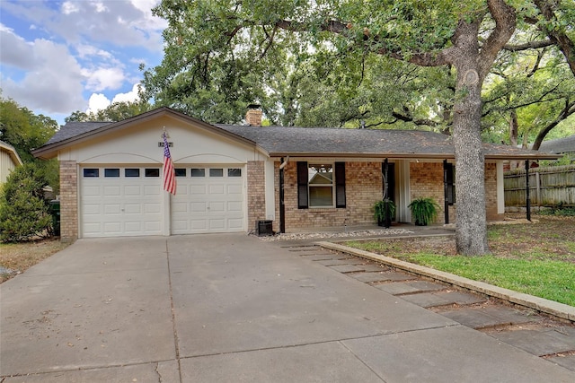 single story home featuring an attached garage, a chimney, concrete driveway, and brick siding