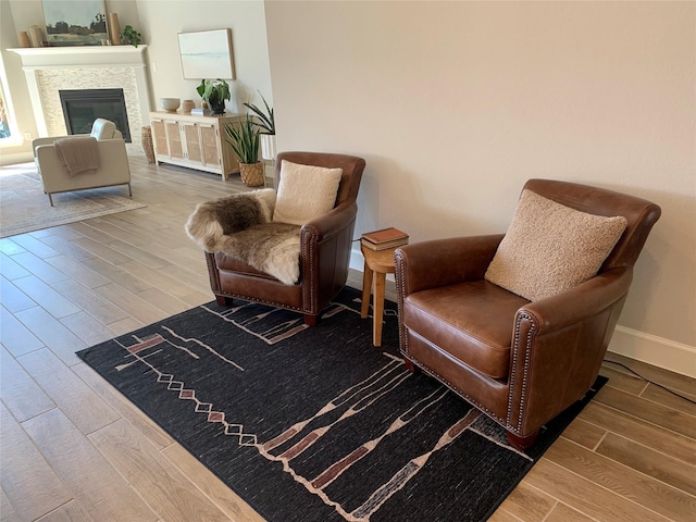 living area featuring baseboards, a glass covered fireplace, and wood tiled floor