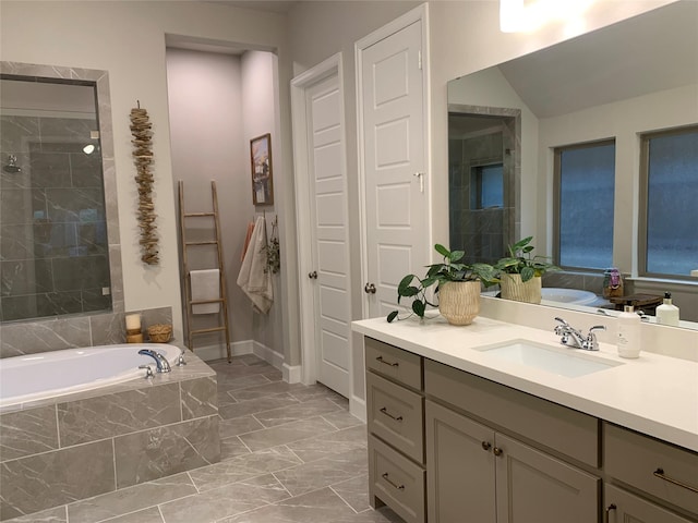 bathroom with baseboards, tiled shower, marble finish floor, vanity, and a bath