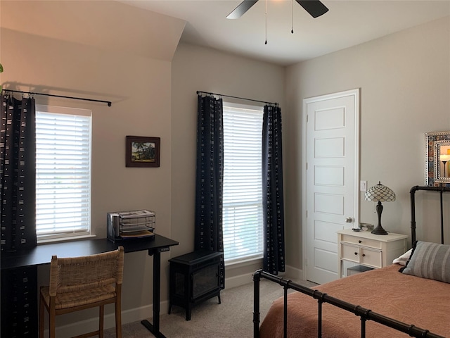 carpeted bedroom featuring multiple windows, baseboards, and a ceiling fan