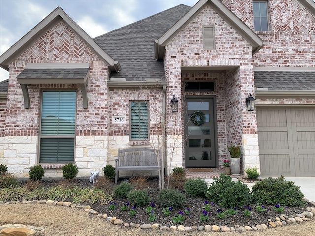 view of front of house with a shingled roof, brick siding, and an attached garage