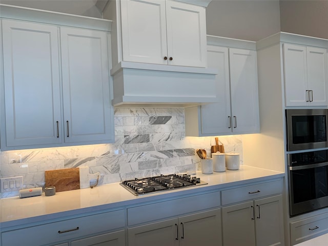 kitchen featuring light countertops, appliances with stainless steel finishes, custom exhaust hood, and tasteful backsplash