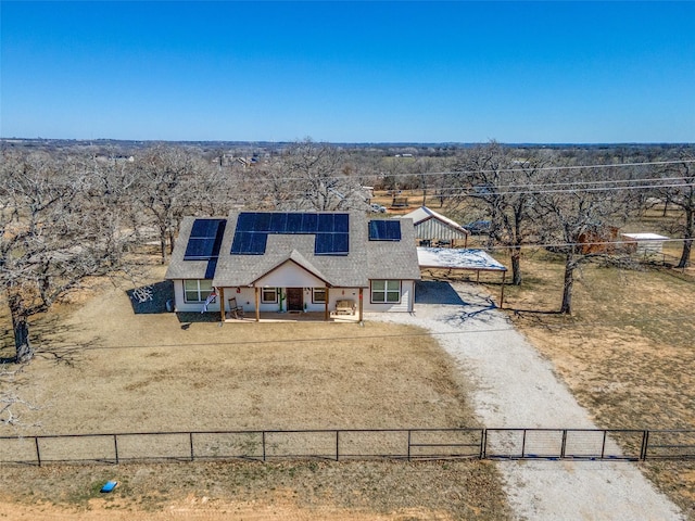 view of front of house with dirt driveway, a porch, fence private yard, and roof mounted solar panels