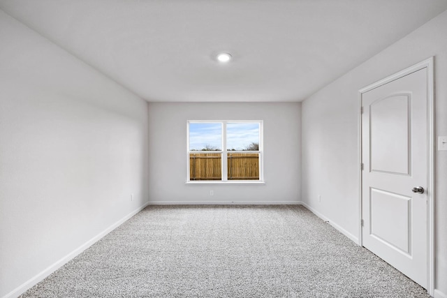 carpeted spare room featuring baseboards