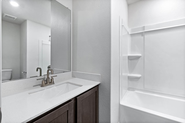 bathroom with visible vents, shower / bathing tub combination, vanity, and toilet