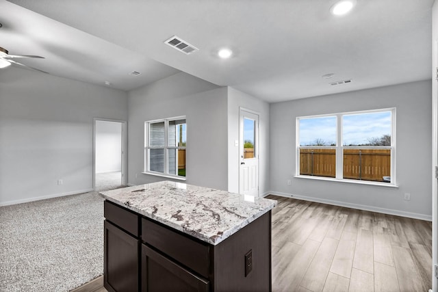 kitchen featuring baseboards, visible vents, open floor plan, and dark brown cabinets