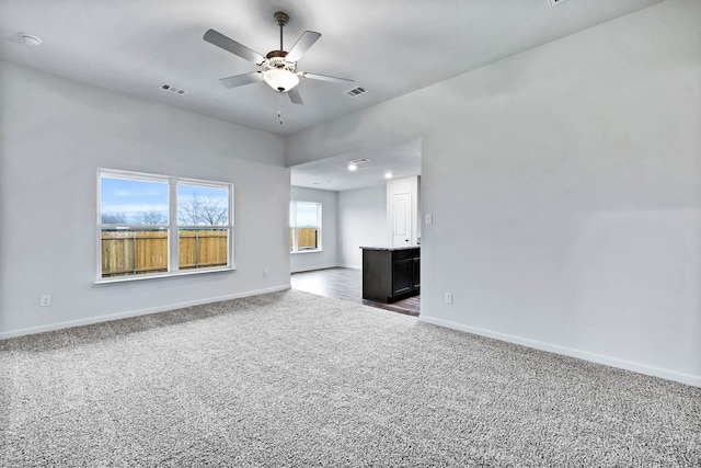 unfurnished living room featuring carpet flooring, visible vents, and baseboards