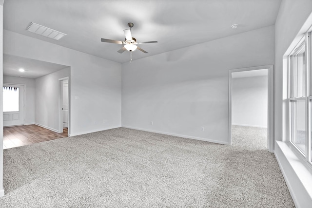 spare room with carpet floors, visible vents, baseboards, and a ceiling fan