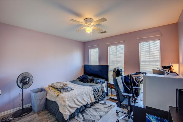 bedroom with ceiling fan, wood finished floors, visible vents, and baseboards