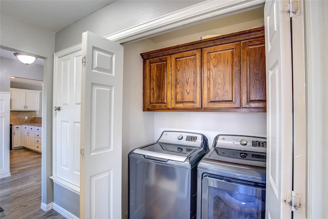 laundry area with cabinet space, wood finished floors, and independent washer and dryer