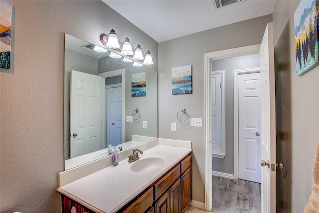 bathroom featuring visible vents, vanity, baseboards, and wood finished floors