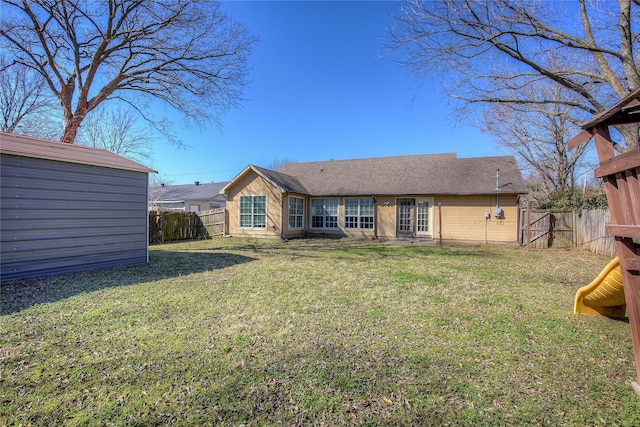 rear view of house with an outbuilding, a yard, and a fenced backyard