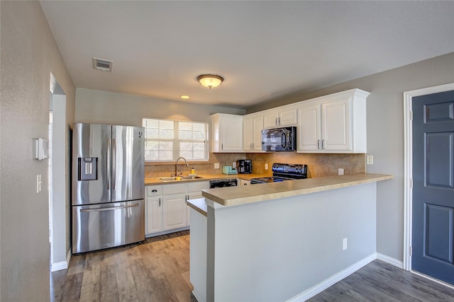 kitchen with black appliances, light countertops, a sink, and visible vents