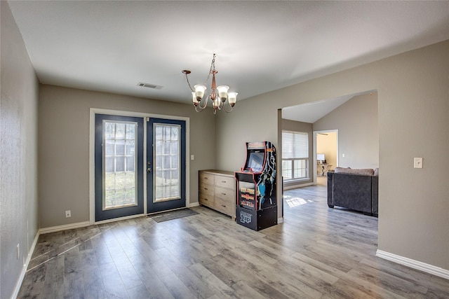 unfurnished room featuring a chandelier, french doors, visible vents, and wood finished floors