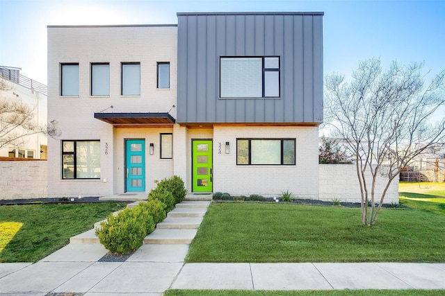 view of front facade with metal roof, brick siding, board and batten siding, and a front lawn