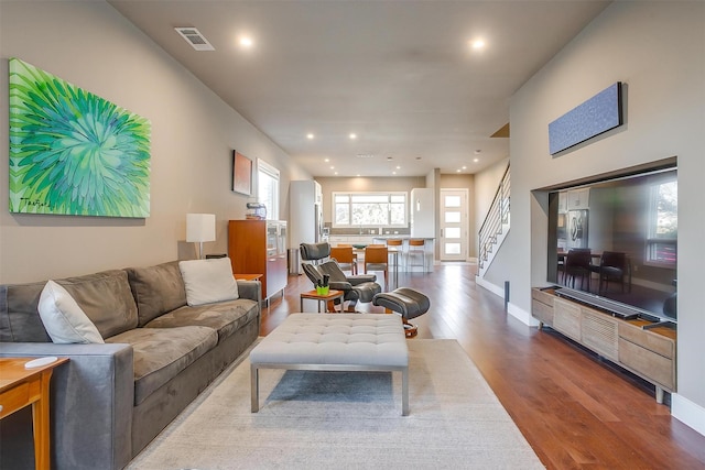 living area featuring recessed lighting, visible vents, wood finished floors, baseboards, and stairs