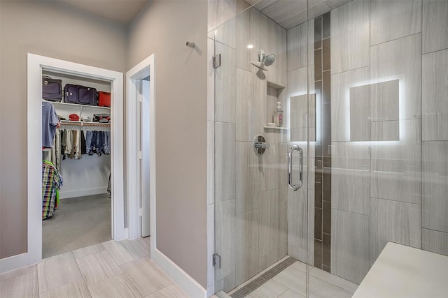 bathroom with a stall shower, a spacious closet, and baseboards