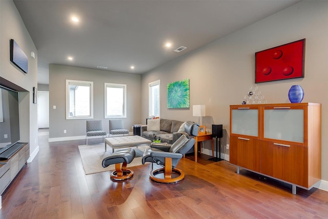 living area featuring baseboards, visible vents, wood finished floors, and recessed lighting