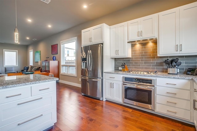 kitchen with stainless steel appliances, dark wood-type flooring, decorative light fixtures, and white cabinets