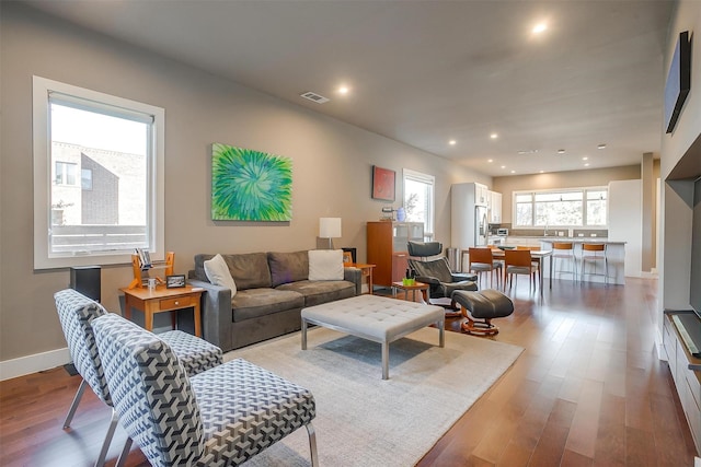 living room featuring baseboards, visible vents, wood finished floors, and recessed lighting