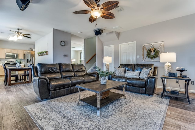 living area featuring visible vents, stairway, a ceiling fan, wood finished floors, and baseboards