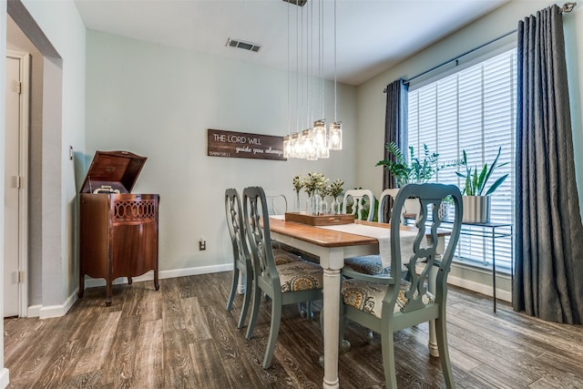 dining area featuring dark wood-style flooring, visible vents, baseboards, and an inviting chandelier