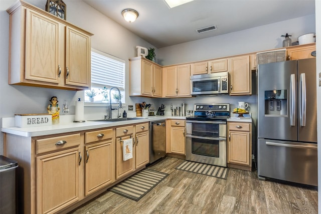 kitchen with stainless steel appliances, a sink, visible vents, light countertops, and dark wood finished floors