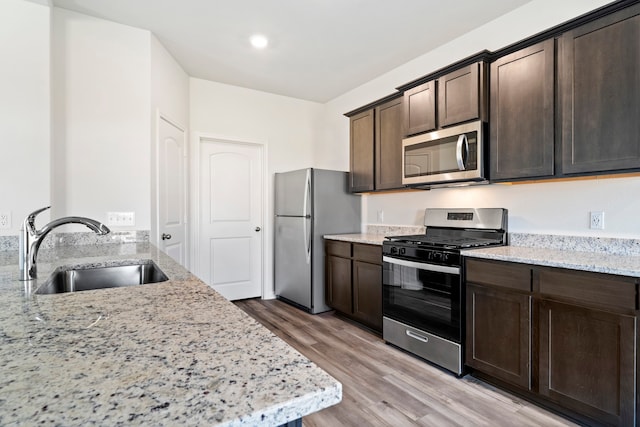 kitchen with stainless steel appliances, a sink, and light stone countertops