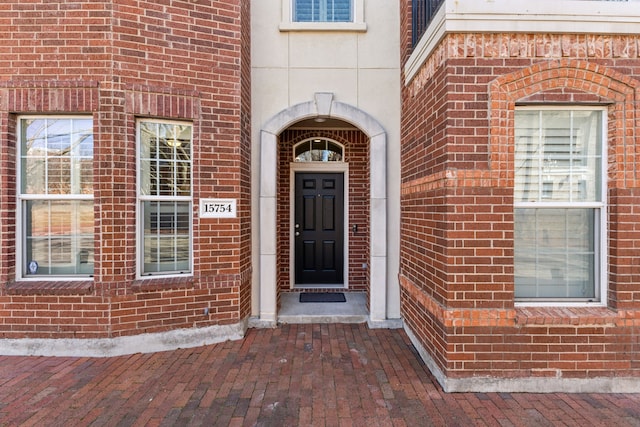 view of exterior entry featuring brick siding