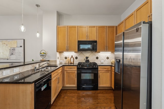 kitchen featuring a peninsula, a sink, dark stone counters, black appliances, and tasteful backsplash