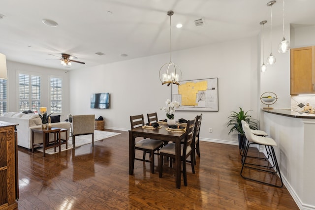 dining space featuring dark wood-style floors, ceiling fan with notable chandelier, baseboards, and visible vents