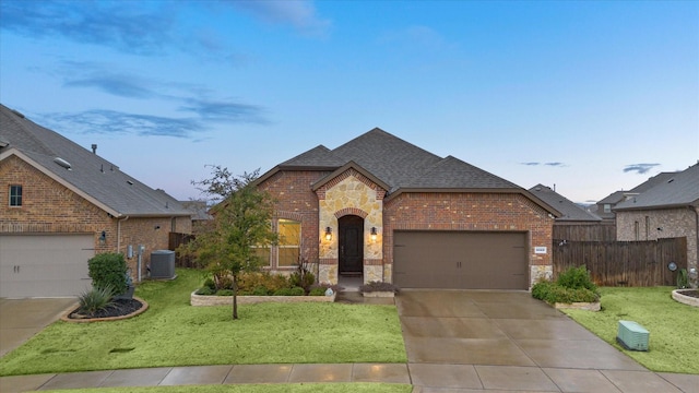 french country inspired facade featuring a shingled roof, stone siding, fence, cooling unit, and brick siding