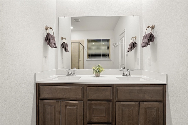 full bathroom featuring double vanity, a stall shower, visible vents, and a sink