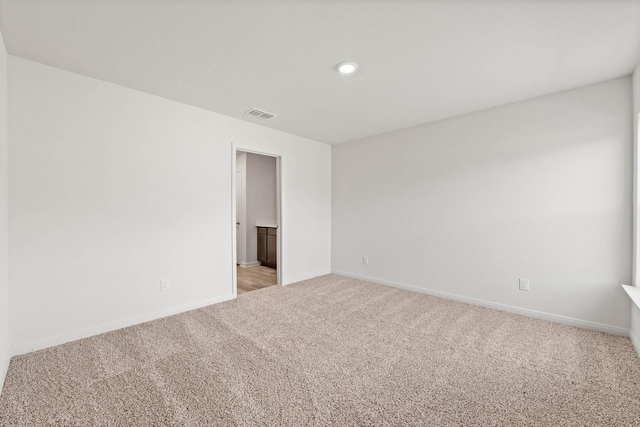 spare room featuring baseboards, visible vents, and light colored carpet