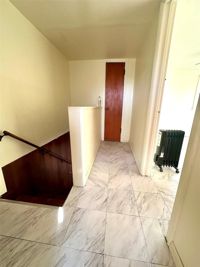 corridor featuring marble finish floor and an upstairs landing