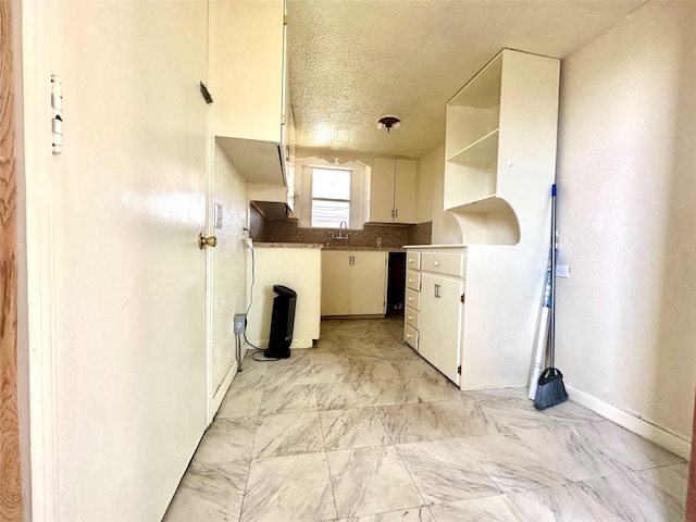 kitchen featuring a textured ceiling, baseboards, white cabinets, marble finish floor, and open shelves