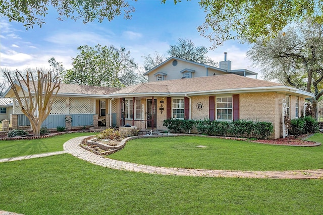 ranch-style house featuring a shingled roof, a front yard, brick siding, and a chimney