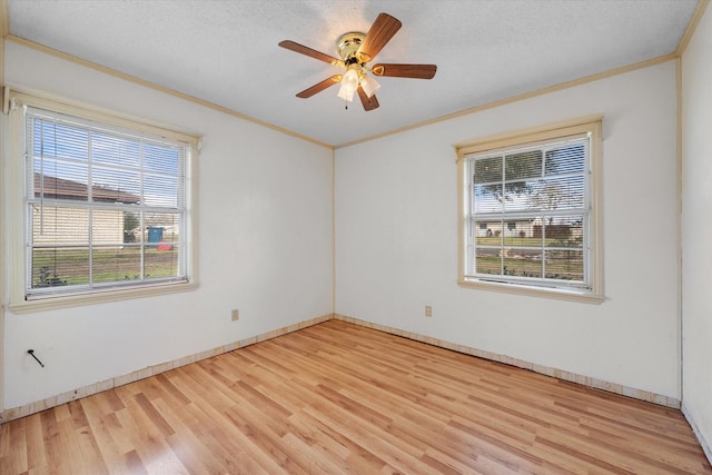 empty room featuring a textured ceiling, a wealth of natural light, light wood-style flooring, and crown molding