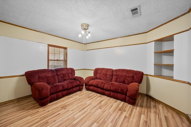 living area featuring light wood-type flooring, visible vents, and crown molding